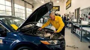 Auto technician performing oil change in active garage