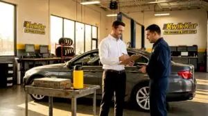Service advisor talking with technician in dealership bay