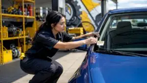 Technician applying oil change sticker on car windshield