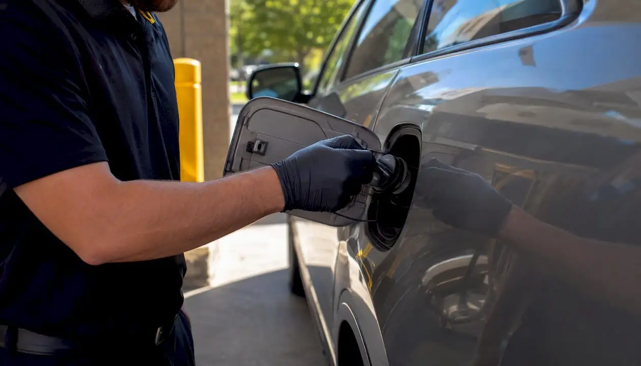 Gloved hand inspecting and tightening vehicle gas cap