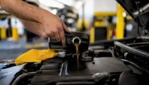 Hands pouring engine oil additives into engine