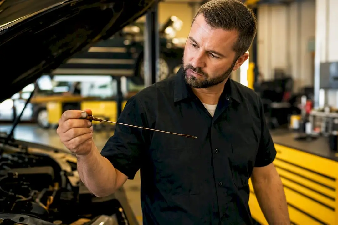 Mechanic checking transmission fluid dipstick in garage