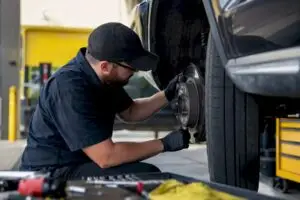 Hands inspecting vehicle brake and tire