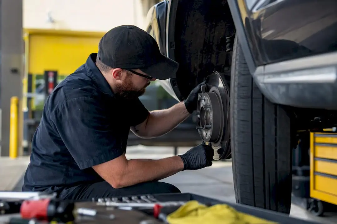 Hands inspecting vehicle brake and tire