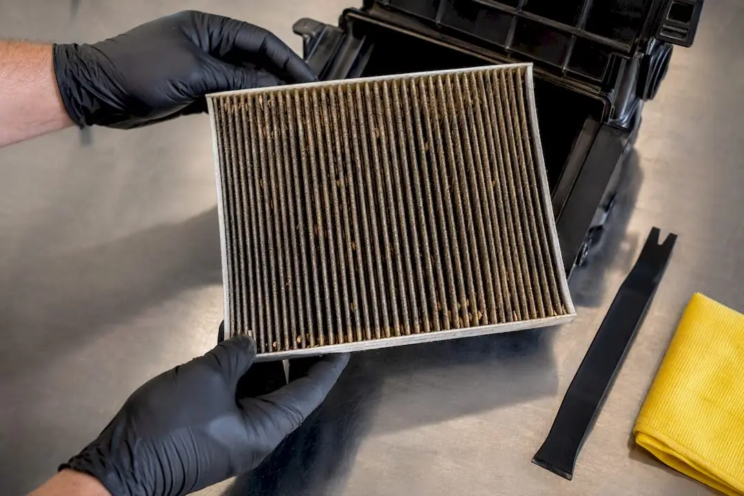 Technician inspecting a dusty cabin air filter