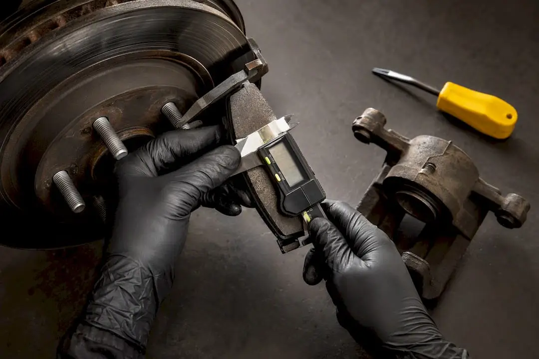 Technician measuring brake pad thickness