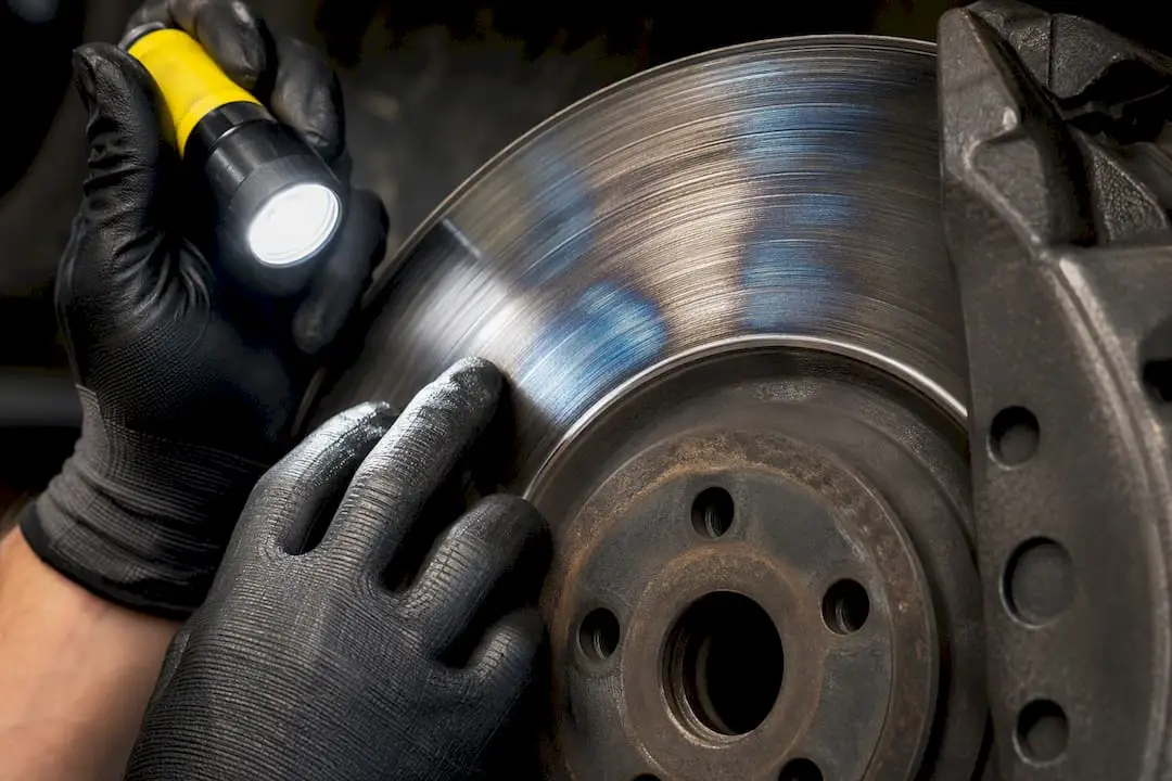 Technician inspecting discolored brake rotor