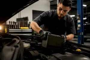 Technician installing anonymous car battery