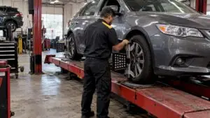 Technician checking wheel alignment on rack
